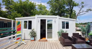 White modular building with wooden deck and plants